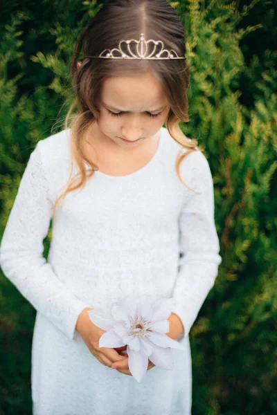 一个穿着白衣 在公园里开着花的小女孩 — 图库照片