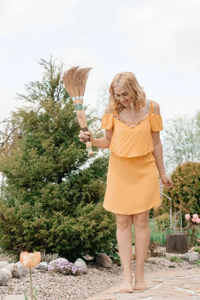 乡村一个穿着黄色浅色衣服的女孩正在整理东西 手里拿着一把扫帚 自然和新鲜空气 景观和设计 — 图库照片