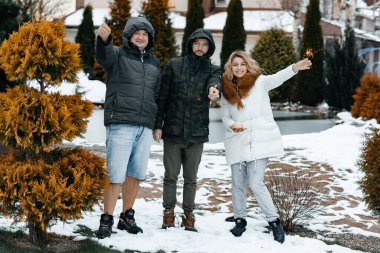Aile yeni yılı ellerinde Bingala ışıklarıyla sokakta durarak kutluyor. Karlı kır evi. Karlı bir gün. Yılbaşı tatilleri. Mutluluk ve aşk kavramı.