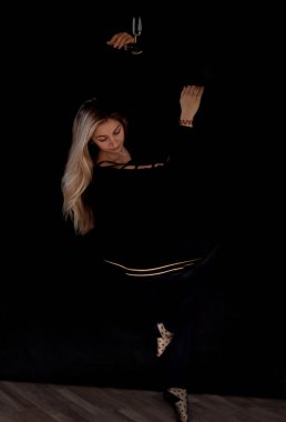 Zarif genç bir kadın karanlık bir odada bir hava halkası üzerinde akrobatik bir element sergiliyor. Jimnastik yüzüğü. Jimnastik ve spor konsepti.