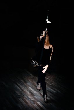 Zarif genç bir kadın karanlık bir odada bir hava halkası üzerinde akrobatik bir element sergiliyor. Jimnastik yüzüğü. Jimnastik ve spor konsepti.