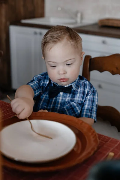 遊んだシャツの少年はしぶしぶ夕食のテーブルで食べる 健康的な食事の概念 障害者のケアの概念 家族の話だ 母の日 コピースペース トーニング — ストック写真