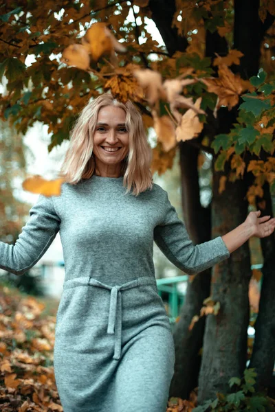 Ein Fröhliches Mädchen Mit Blonden Haaren Einem Grauen Kleid Wirft — Stockfoto