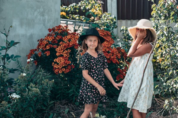 Duas Meninas Vestidos Chapéus Estão Andando Jardim Dacha Flores Florescendo — Fotografia de Stock