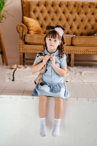 一个穿着蓝色衣服的女孩手里拿着一个玩具坐在那里 快乐的婴儿微笑 祝你玩得愉快儿童风格和时尚的概念 唐氏综合征 复制空间 Toning案 — 图库照片