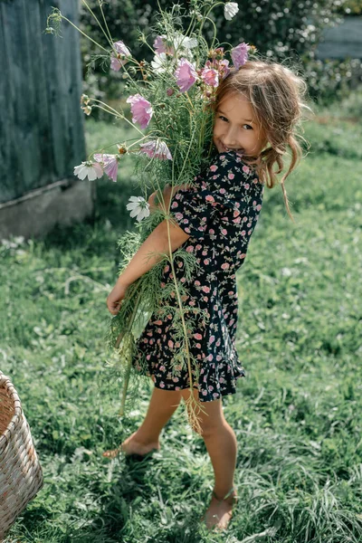 Маленька Дівчинка Чорній Сукні Тримає Величезний Букет Польових Квітів Руках — стокове фото