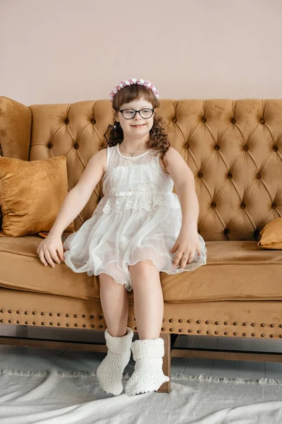 Una Niña Con Vestido Blanco Gafas Sienta Sofá Marrón Estudio —  Fotos de Stock