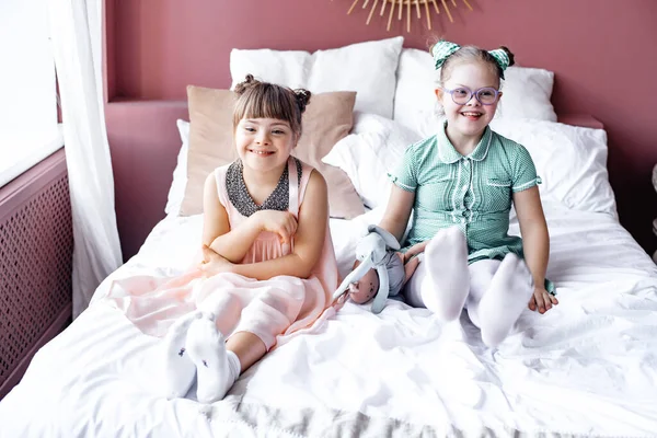 Två Små Leende Flickor Sitter Sängen Och Håller Mjuka Leksaker — Stockfoto