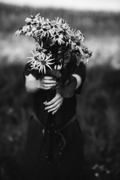 一张白纸黑字的照片 是一个长头发的漂亮姑娘在田野里采摘了一束花的照片 走在乡间 带着一束雏菊的女孩 — 图库照片
