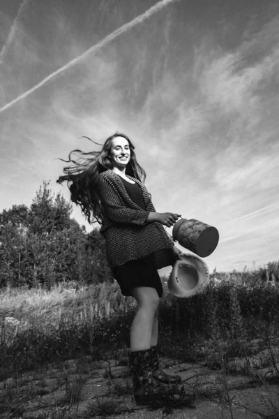 森林附近的一张黑白照片 照片上的女孩穿着长发 手里拿着一顶帽子 那女孩到乡下去散散步 — 图库照片