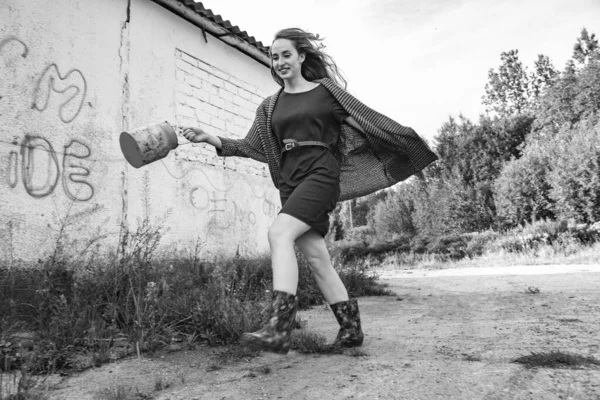 一个穿着长发头戴礼帽的漂亮姑娘手里拿着铁桶走在森林边 农村地区 — 图库照片
