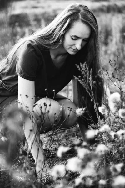 Çiçeklerin Yanında Oturan Uzun Saçlı Bir Kızın Siyah Beyaz Fotoğrafı — Stok fotoğraf