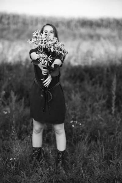 野の花の花束を集めている長い髪を持つ美しい少女の黒と白の写真 田舎を歩きなさい 女の子とともにA花束のデイジー — ストック写真