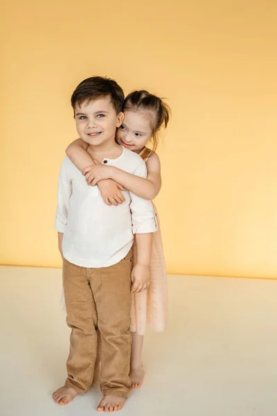 Una Niña Vestido Abraza Niño Sonriente Fondo Fondo Amarillo Sólido —  Fotos de Stock