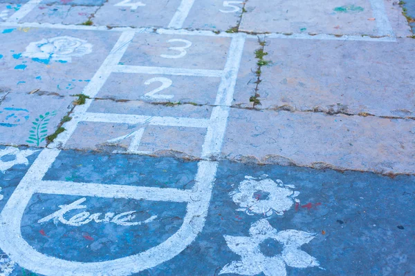 Hopscotch en un suelo de asfalto con dibujos de tiza de números y — Foto de Stock