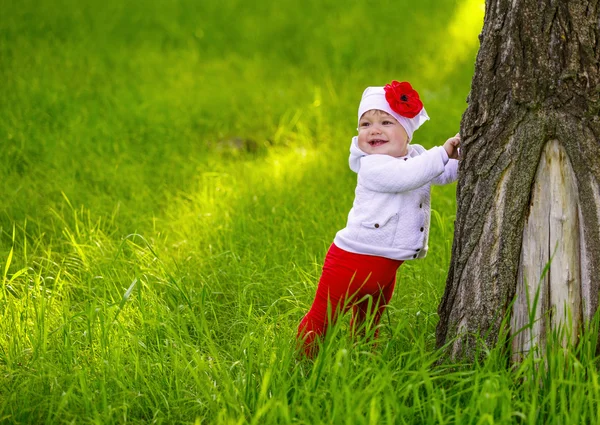 Dziecko stoi w pobliżu drzewa na zielonej trawie — Zdjęcie stockowe