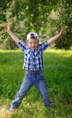 Küçük çocuk parkta yeşil çimenlerin üzerinde atlama