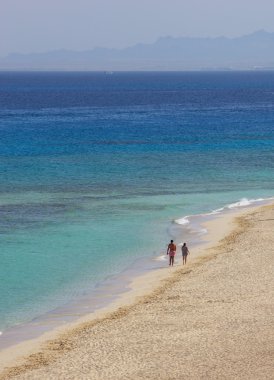 Erkek ve kadın ıssız sahil boyunca gidiyorsun