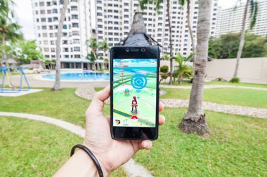 Bir akıllı telefon tutarak ve Pokemon Go oynayan bir kişi el görünümü kapatın