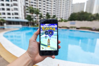 Bir akıllı telefon tutarak ve Pokemon Go oynayan bir kişi el görünümü kapatın