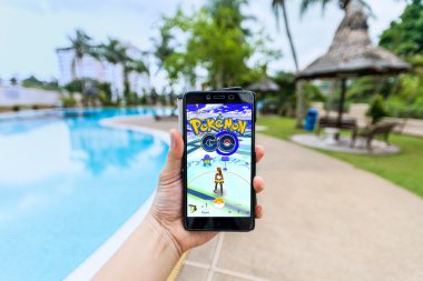 Bir akıllı telefon tutarak ve Pokemon Go oynayan bir kişi el görünümü kapatın