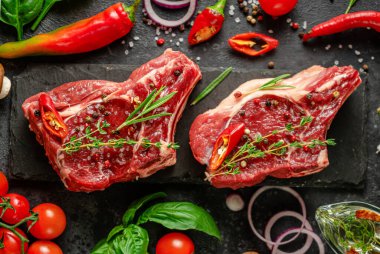 Baharatlı, sebzeli ve koyu arkaplanlı taze kemik biftekleri. Düz yat, kapat..