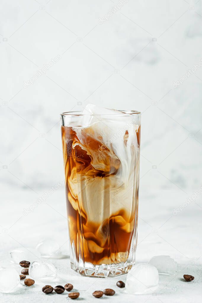 Iced Greek coffee frappe with ice cubes and beans on gray concrete background. Copy space