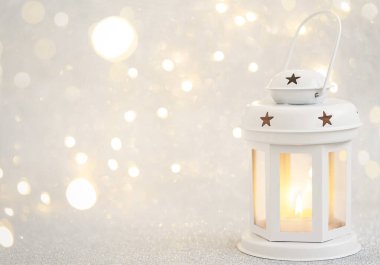 Odaklanamayan bokeh arka planda, beyaz fenerde yanan mum. Kış tatili kavramı