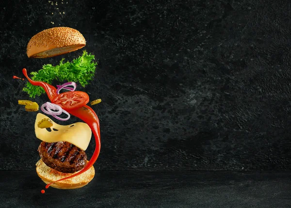 Karanlık arka planda yüzen malzemeli hamburger. Yaratıcı natürmort konsept ve reklam