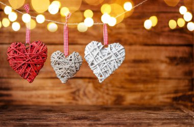 Ahşap arka planda Bokeh ile asılı üç kullanışlı kalp. Sevgililer Günü tebrik kartı.