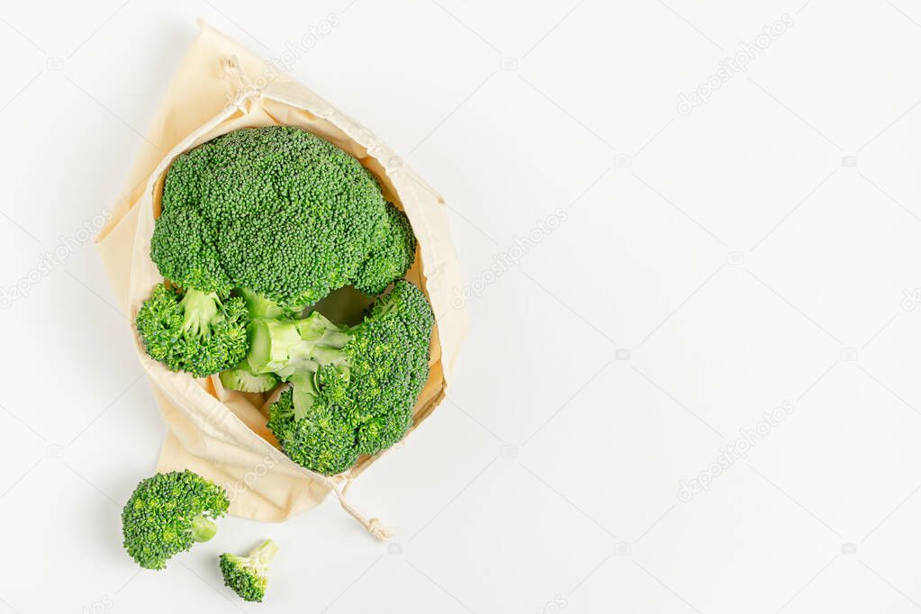 Zero waste food storage. Raw broccoli in eco bag on white background. Top view, copy space