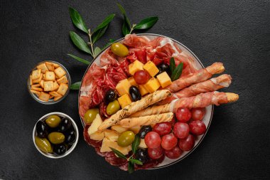Siyah arkaplanda çeşitli İtalyan antipasto seti, üst görünüm.