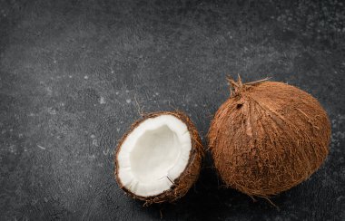 Koyu beton arka planda bir buçuk hindistan cevizi. Boşluğu kopyala.