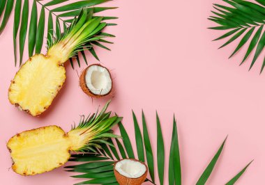 Pembe yaz arka planında yarım ananas ve hindistan cevizi. Düz yat, boşluğu kopyala.