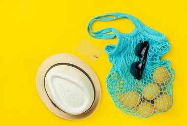 Şapka, güneş gözlüğü, limonlu yeniden kullanılabilir çanta ve sarı yaz arka planında kredi kartı. İnternetten alışveriş.