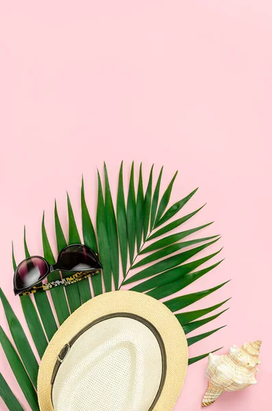 Шляпа, солнцезащитные очки и пальмовый лист на розовом фоне. Вид сверху, пространство для копирования. — стоковое фото