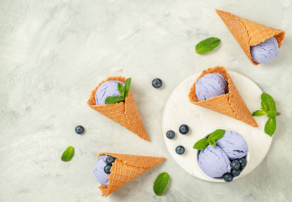 Blueberry ice cream waffle cones on concrete gray background. Flat lay, copy space.