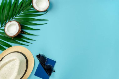 Gezgin aksesuarları, hindistan cevizi yarıları ve mavi arka planda palmiye yaprağı. Düz yat, boşluğu kopyala.