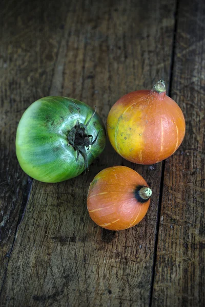 Red kuri squashes and beefsteak tomato on a dark wooden table