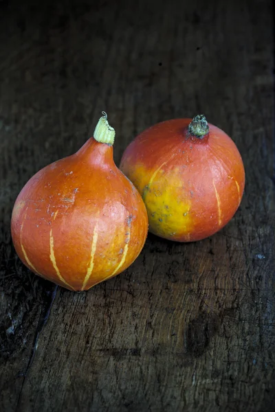 Red kuri squashes on a dark wooden table 1