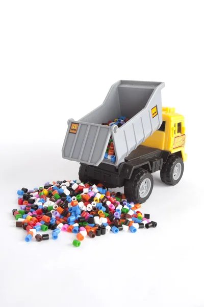 Isolierter Spielzeug-LKW entsorgt Perlen auf einer Weile Hintergrund — Stockfoto