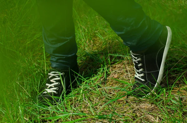 Női láb farmer és sport cipő. Cipők, egy fából készült padon park közelről. — Stock Fotó