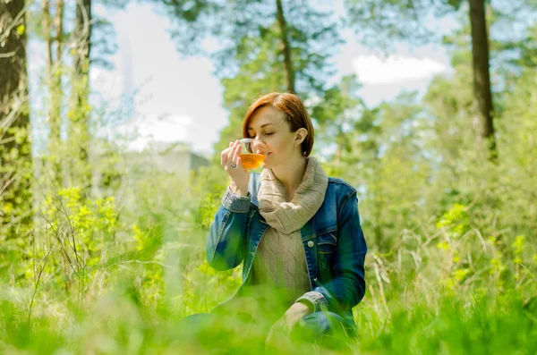 Одинокая девушка наслаждается чашкой зеленого чая в лесу — стоковое фото