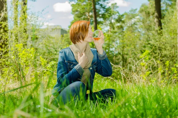 Одинокая девушка наслаждается чашкой зеленого чая в лесу — стоковое фото