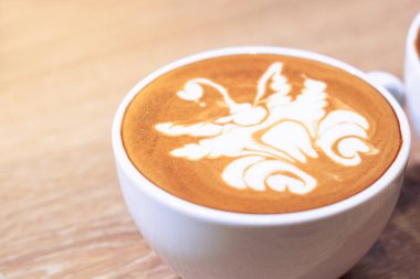 Sütlü sütlü bir fincan kahveyi eski tarz kafe 'nin ahşap masasında servis et.