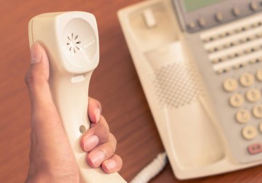 Yakın plan iş adamı eski ofis telefonunu iş iletişimi için masanın üzerinde tutuyor, çok dilli retro iç mekan 1990 model telefon geçmişi