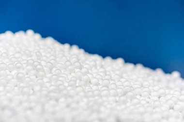 Beyaz polistiren köpük boncuk topu, kırılgan şeyler için yapay köpük makinesinden düşerek modern lüks arka planda, fotokopi alanı ve küresel ısınma koruması atığı olan mavi kutuya konur.