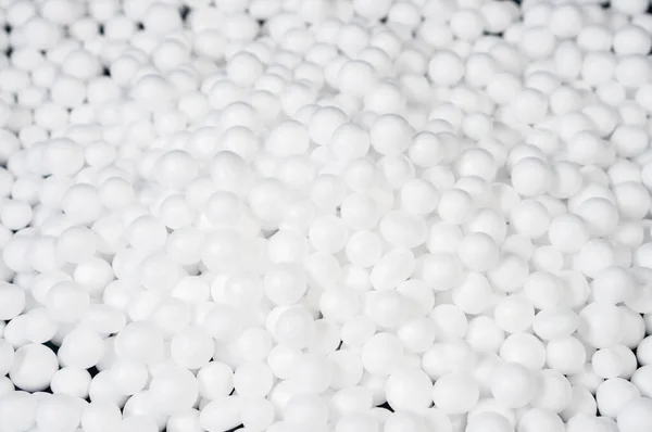 white polystyrene foam beads ball drop from Styrofoam machine for fragile stuff packaging box, plastic texture background decoration