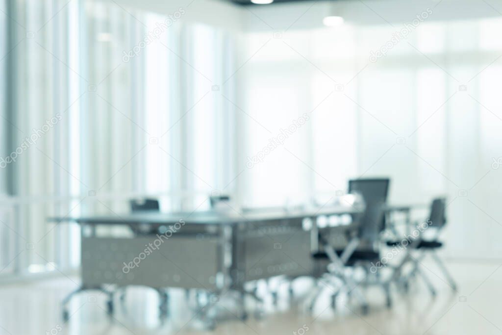 Modern Interior meeting room with evening sunset from clean glass windows, empty large conference space with chairs and tables furniture, blurred business background