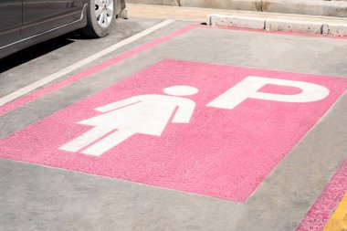 Benzin istasyonunun beton sokak zemininde boş kadın park yeri sembolü, kadın arabaları için kadın öncelikli park alanı tabelası.